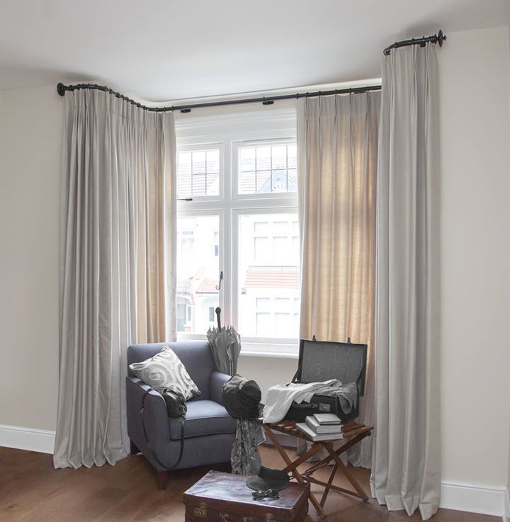 a living room filled with furniture and a large window covered in white drapes