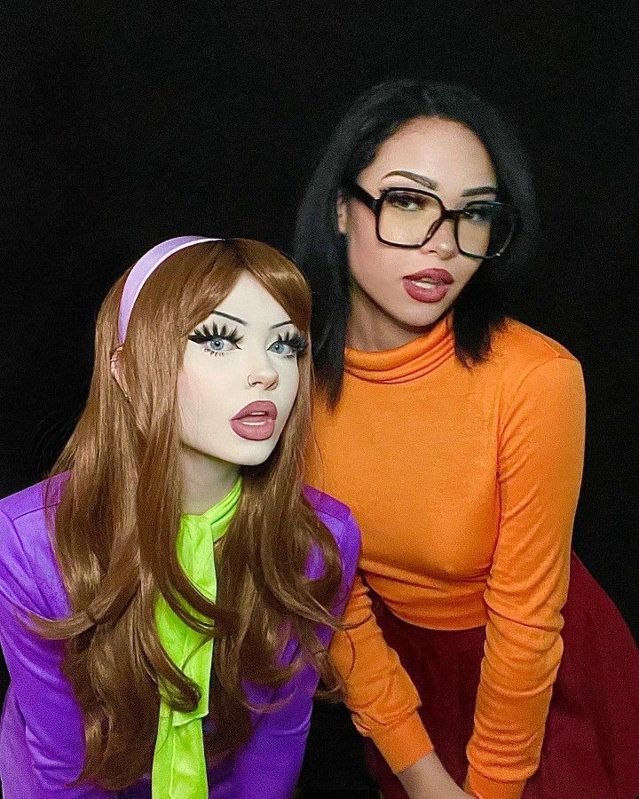 two mannequins dressed up as women with long hair and glasses, one wearing an orange top