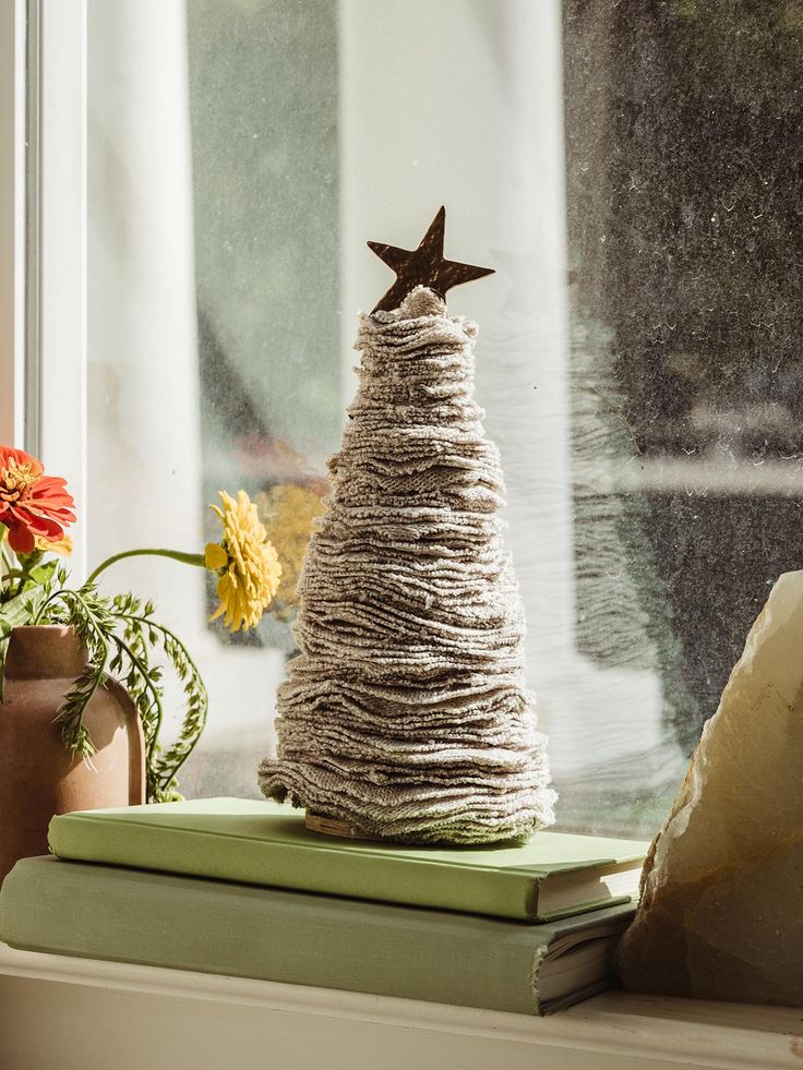 a small christmas tree sitting on top of a stack of books