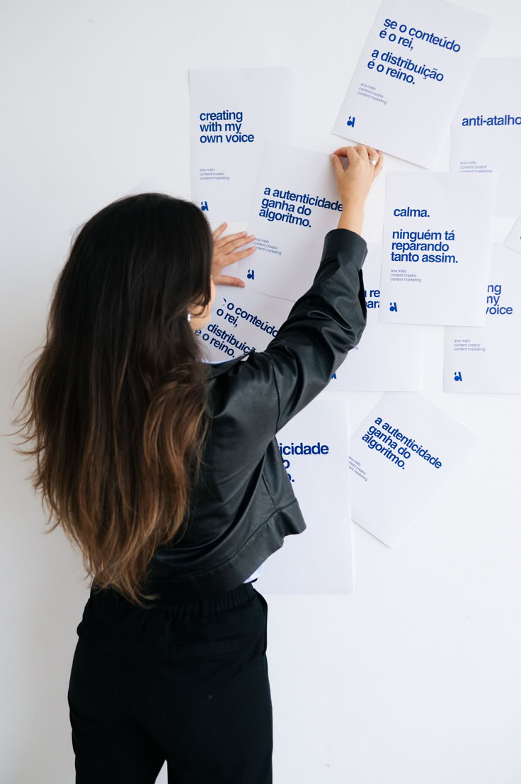 a woman writing on some white paper with her hand in the air and several other papers behind her