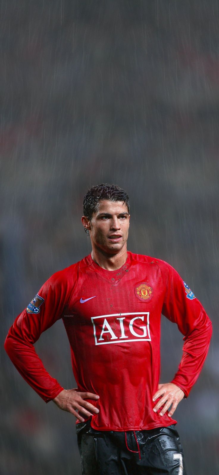 a man standing in the rain with his hands on his hips wearing a red shirt