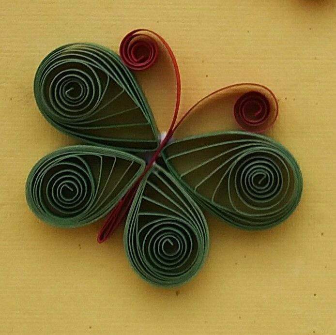 an origami butterfly made out of green paper on a yellow surface next to scissors