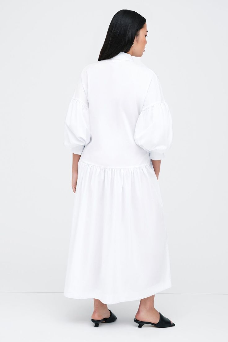 Meet our Ada Dress, the ultimate warm weather staple. She's a midi shirtdress handcrafted from 100% European poplin cotton, featuring pockets and a dropped gathered waistline that falls over your frame with ease. Her clean lines and sharp collar harmonize with dramatic dropped shoulders and full-bodied sleeves, elevating your style for any occasion.[SPLIT] Shannon, in white, is 5'8" (173 cm) tall, wearing size M. Yada, in light blue, is 5'9" (175 cm) tall, wearing size XS. Maritza, in black and Billowy Cotton Dress For Fall, Cotton Maxi Dress With Gathered Puff Sleeves, Cotton Maxi Dress With Puff Sleeves, Spring Cotton Midi Dress With Pleated Waist, Cotton Day Dresses With Gathered Sleeves, Smocked Relaxed Fit Midi Dress, Cotton Midi Dress With Pleated Hem, Cotton Puff Sleeve Long Sleeve Dress For Daywear, Cotton Midi Dress With Pleated Waist For Spring