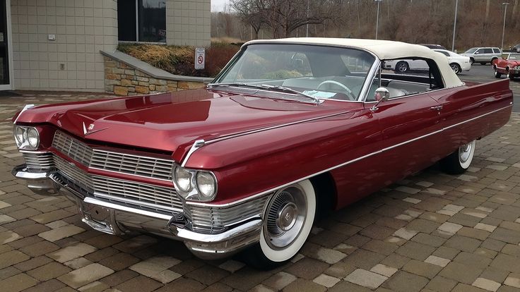 an old red and white car parked in front of a building