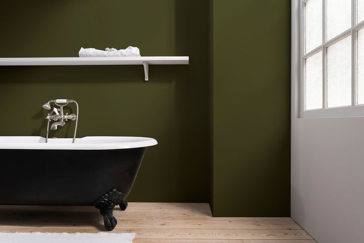 a bath tub sitting next to a toilet in a bathroom under a window with shelves above it