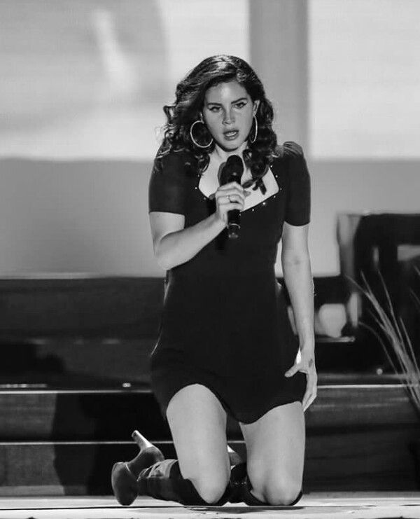 a black and white photo of a woman on stage with a microphone in her hand