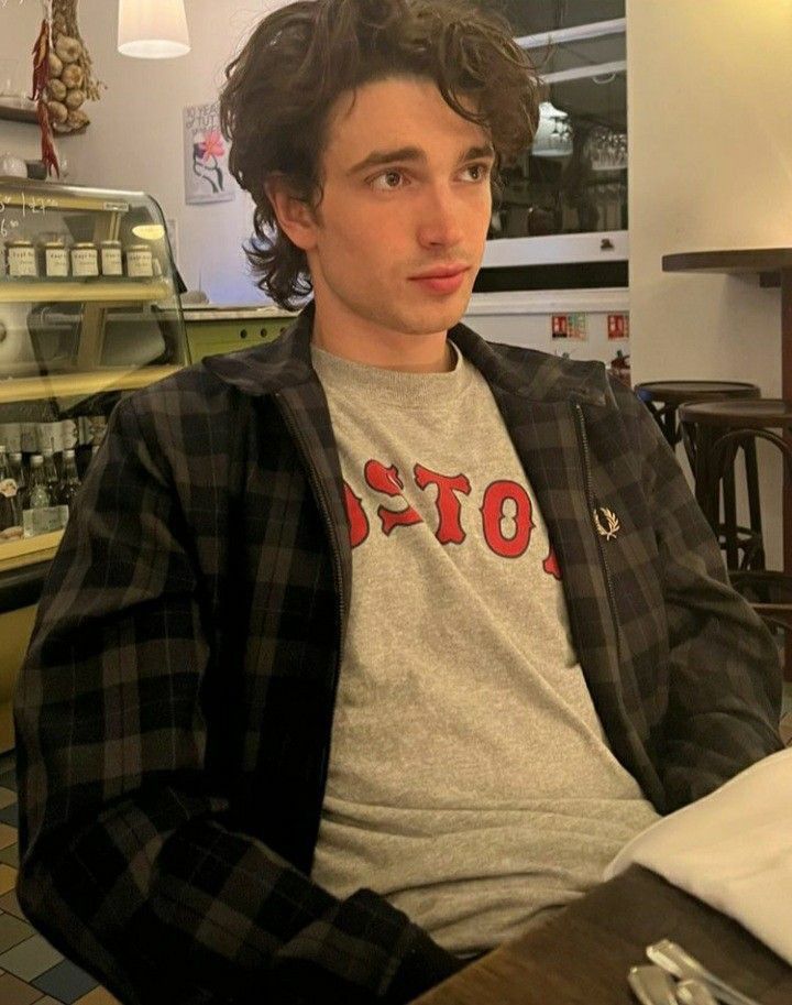 a young man sitting at a table in a restaurant looking off to the side with his hands on his hips