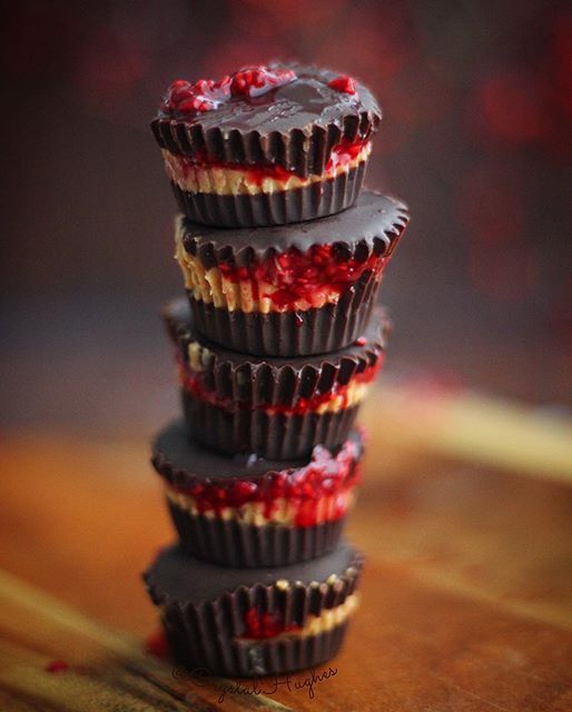 three chocolate cups with raspberry toppings stacked up on top of each other