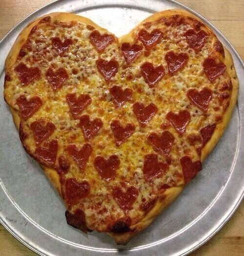 a heart shaped pizza sitting on top of a metal plate