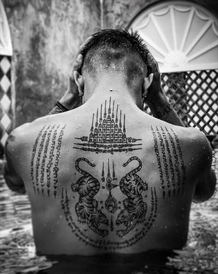 a man with tattoos on his back sitting in the water