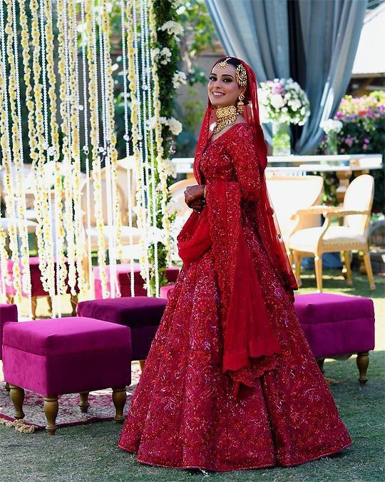 a woman in a red wedding dress standing next to a purple chair and table with flowers on it