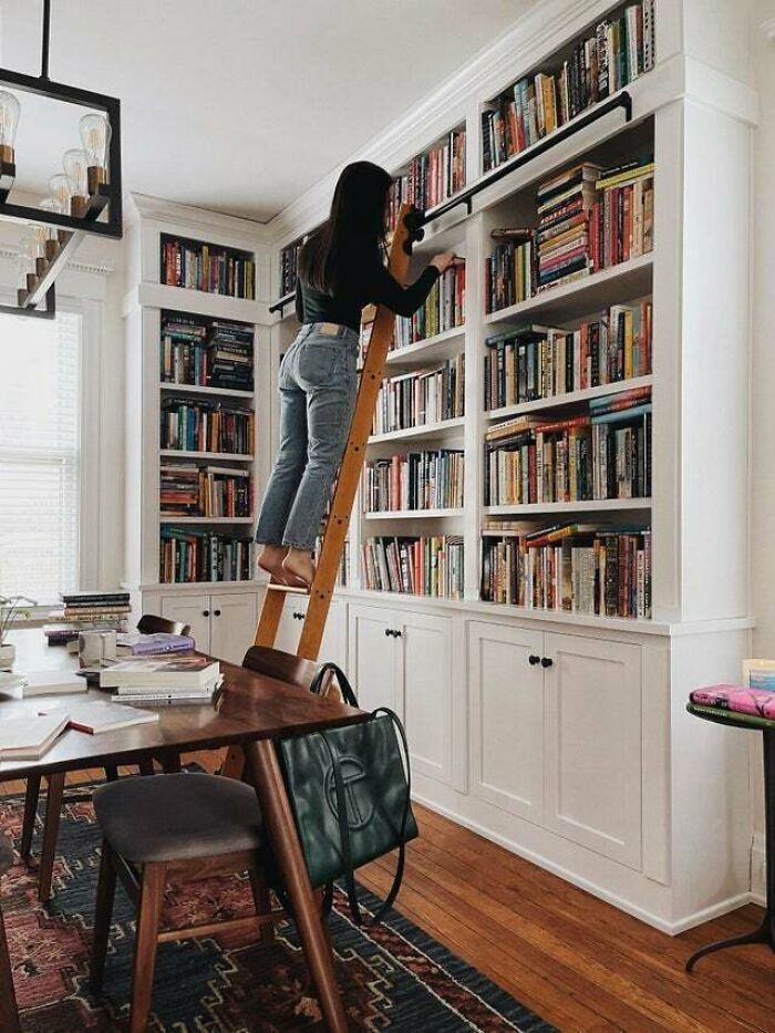 a woman standing on a ladder in front of a bookshelf