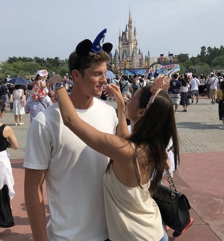 a man and woman standing next to each other in front of a castle with lots of people