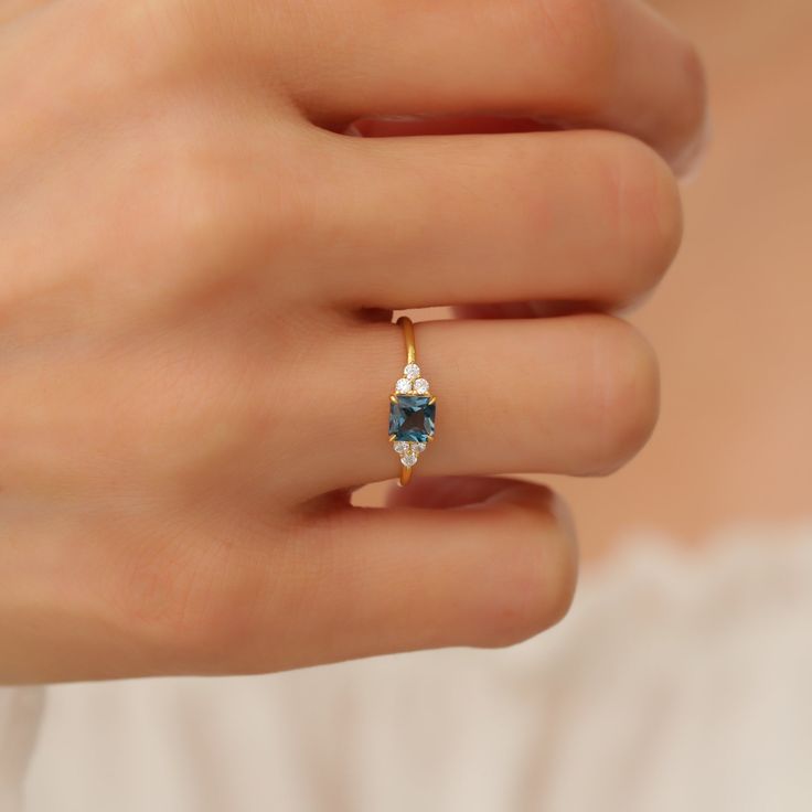 a woman's hand wearing a gold ring with blue and white stones on it