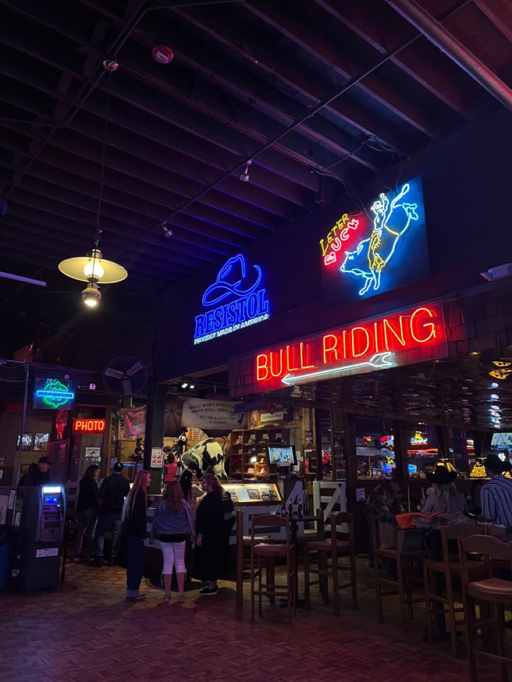 people are standing in line at the entrance to a building with neon signs on it