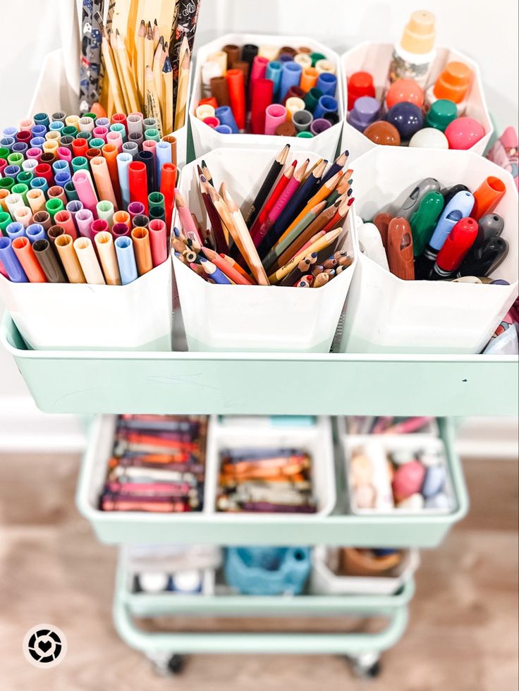 an assortment of crayons and pencils in containers on a cart with wheels