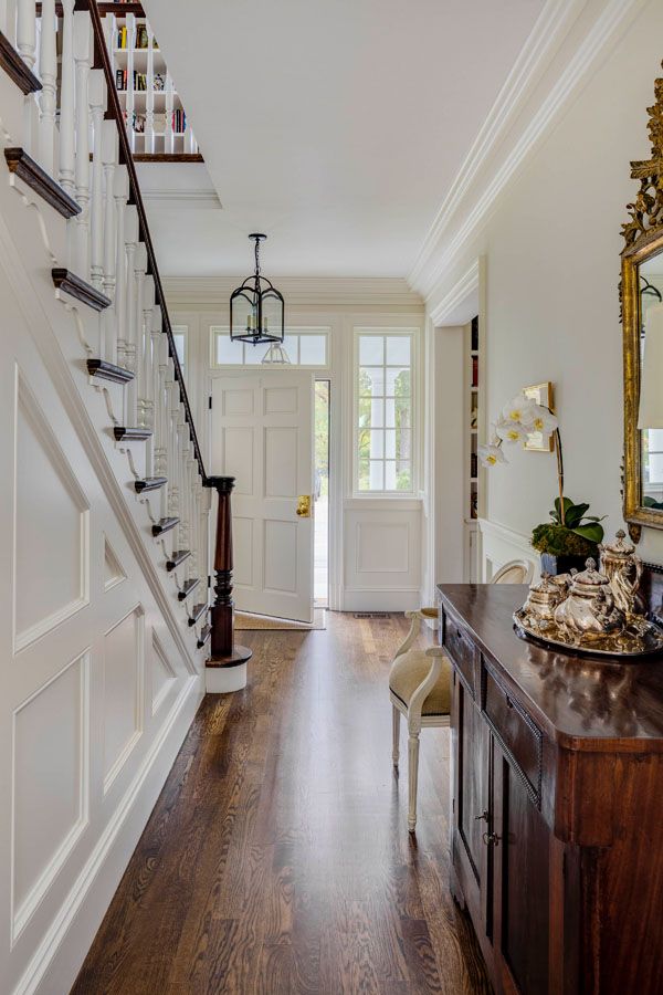 a hallway with wooden floors and stairs leading to the second floor, along with a large mirror on the wall