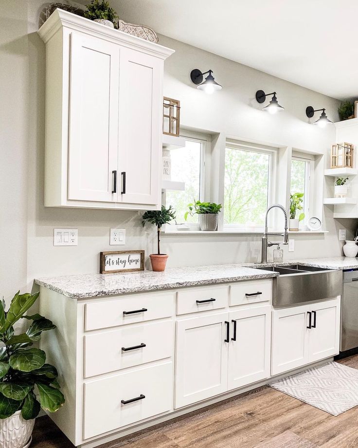 a clean kitchen with white cabinets and stainless steel dishwasher on the countertop