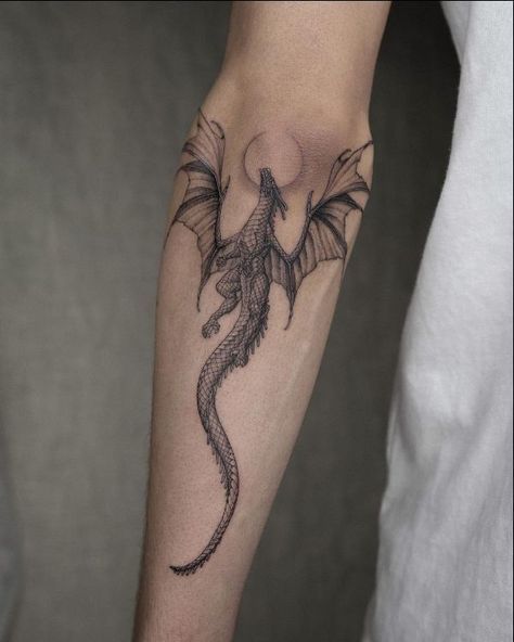 a black and grey dragon tattoo on the arm