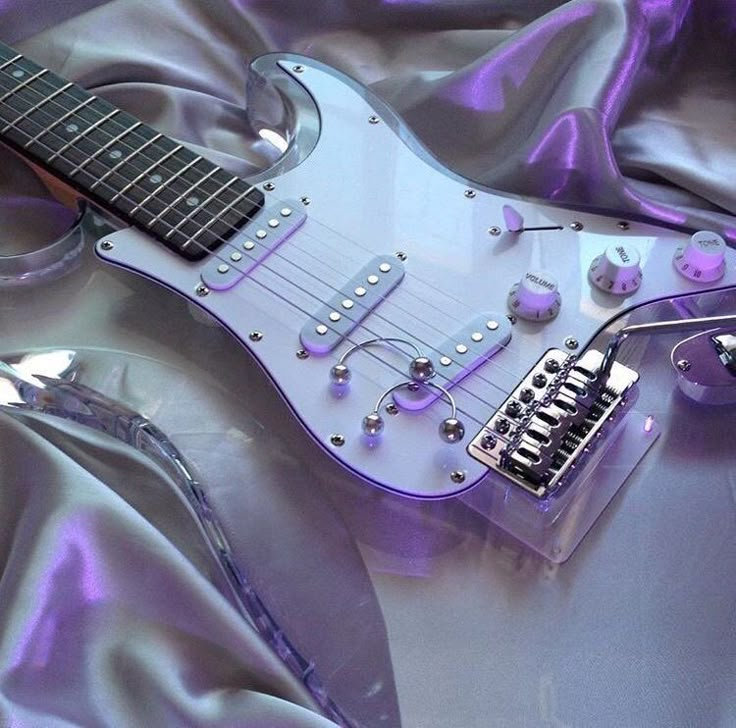 an electric guitar sitting on top of a purple cloth