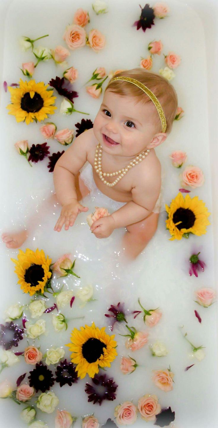 a baby sitting in a bath with sunflowers and flowers all around her body