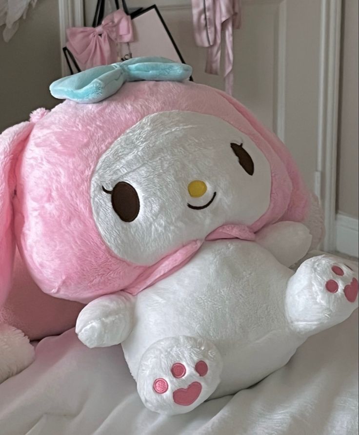 a pink and white stuffed animal sitting on top of a bed