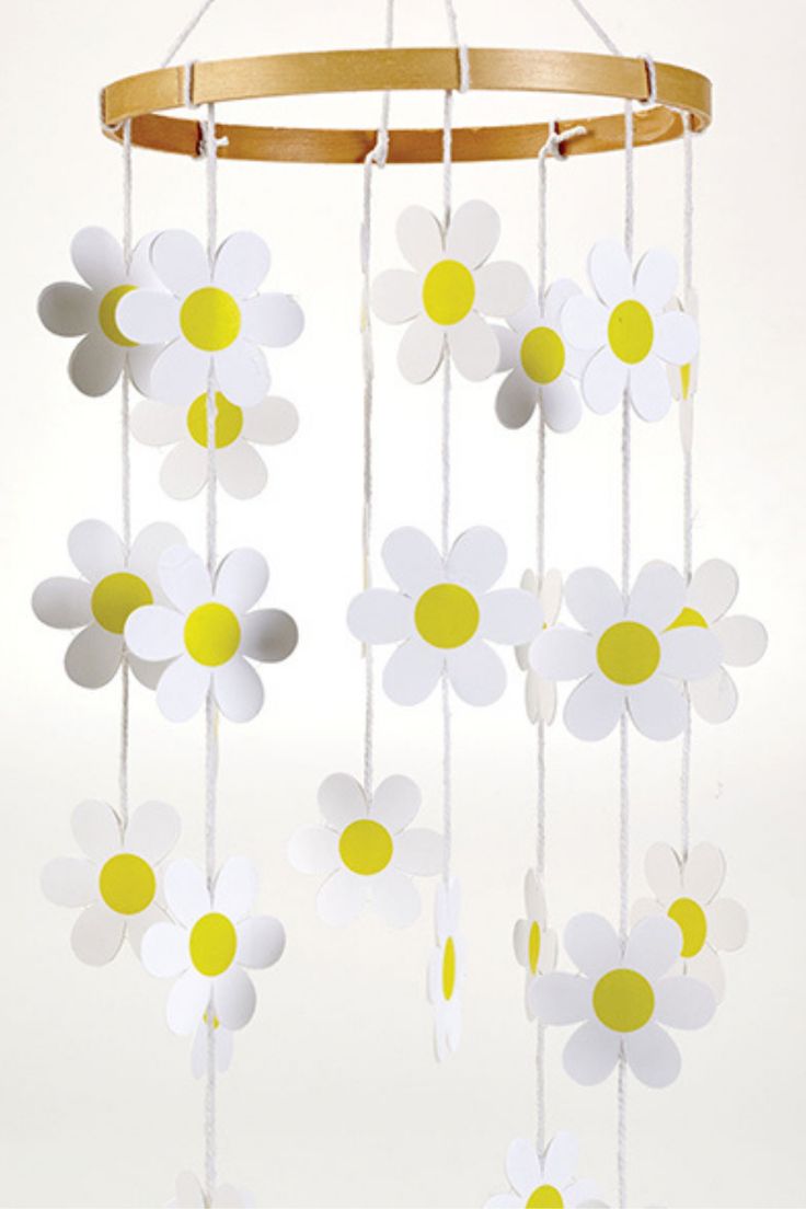 a wind chime with white and yellow flowers hanging from it