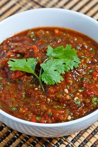 a white bowl filled with chili and garnish on top of a woven place mat