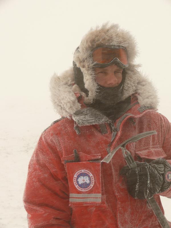 a man standing in the snow wearing a red jacket