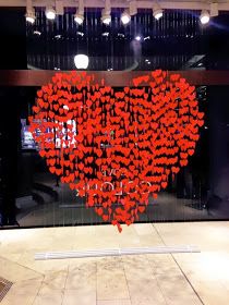 a large heart made out of red hearts in front of a glass window with the words love you written on it