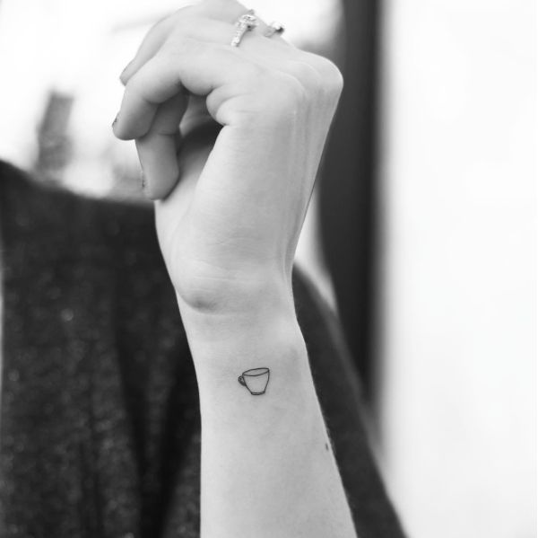 a person with a small tattoo on their arm holding up her hand and looking at the camera