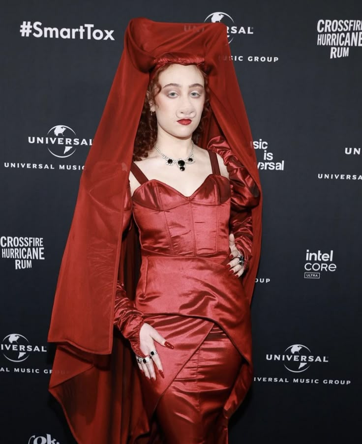 a woman in a red dress with a veil on her head and hands behind her head