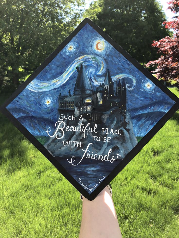 someone is holding up a graduation cap with a painting on it