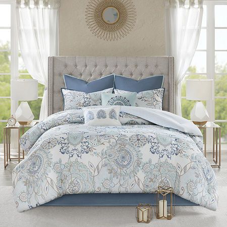 a bed with blue and white comforters in a bedroom next to two nightstands