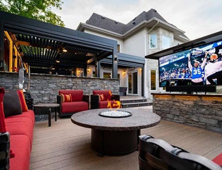 an outdoor living area with couches, tables and a flat screen tv on the wall