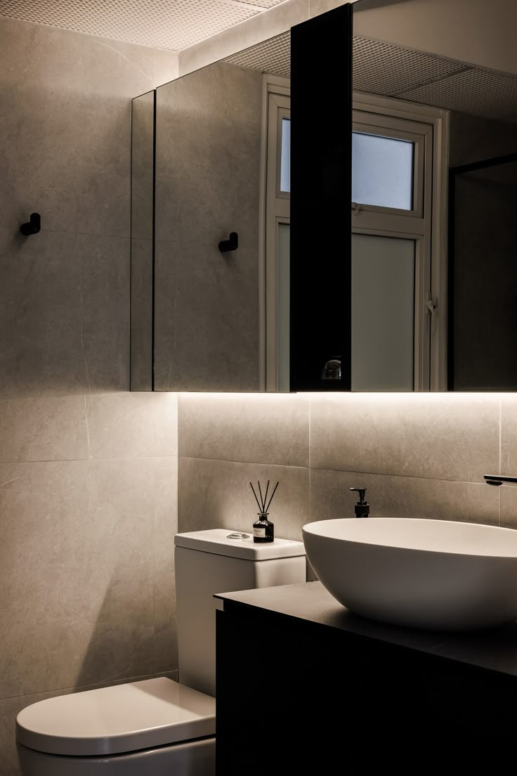 a bathroom with a sink, toilet and mirror above it's countertop area