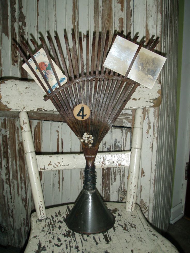 an old chair with some kind of fan on it's back and pictures hanging from the top