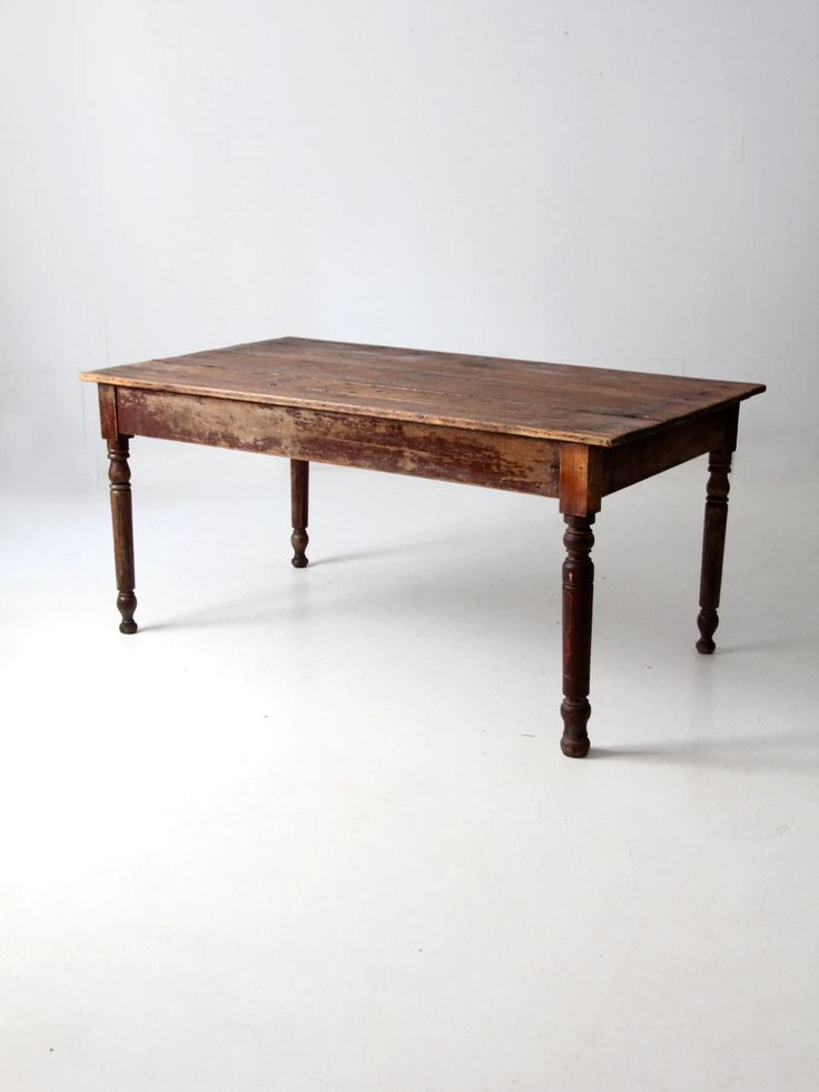 an old wooden table sitting on top of a white floor