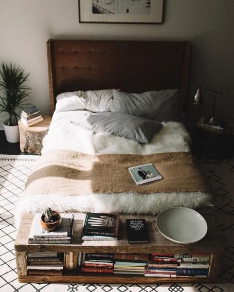 a bed that has some books on it and a bowl in front of the bed