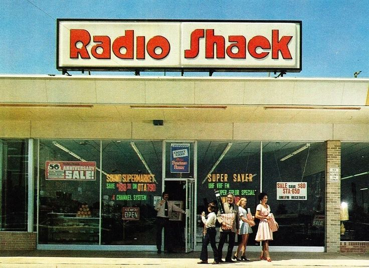 three people standing outside of a radio shack