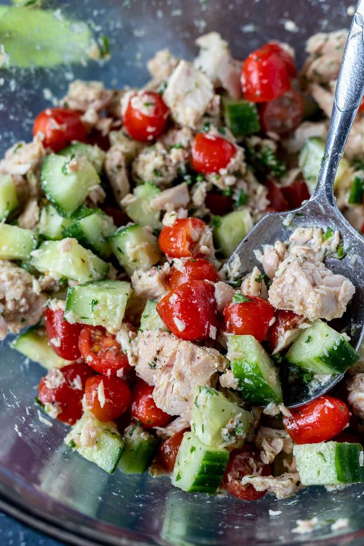 a bowl filled with cucumber, tomatoes and tuna salad