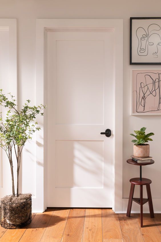 a white door with a potted plant next to it on a wooden stool in front of the door