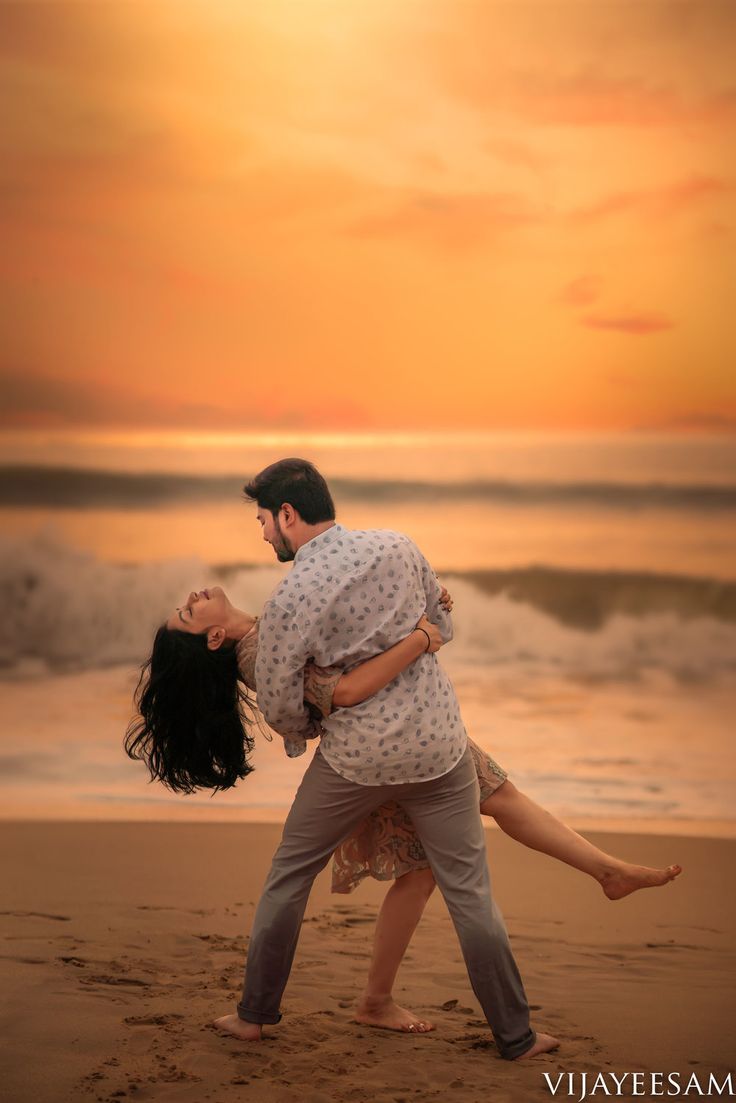 a man and woman dancing on the beach at sunset