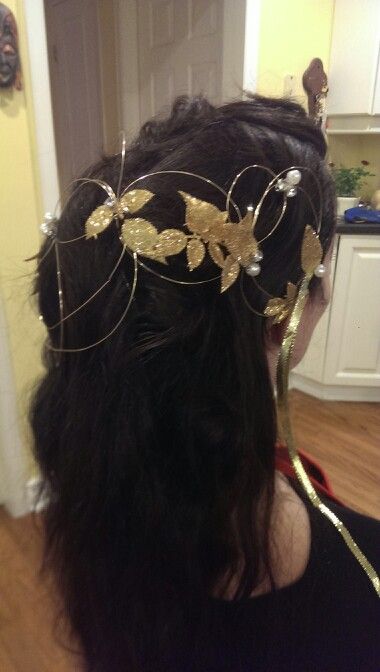 the back of a woman's head wearing a gold leaf tiara in a kitchen