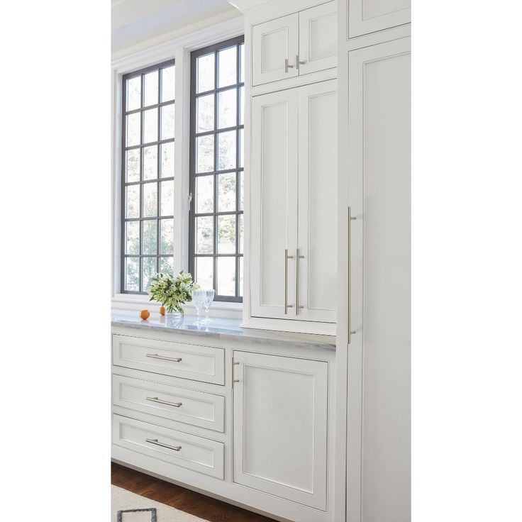 a kitchen with white cabinetry and marble counter tops, along with an area rug on the floor