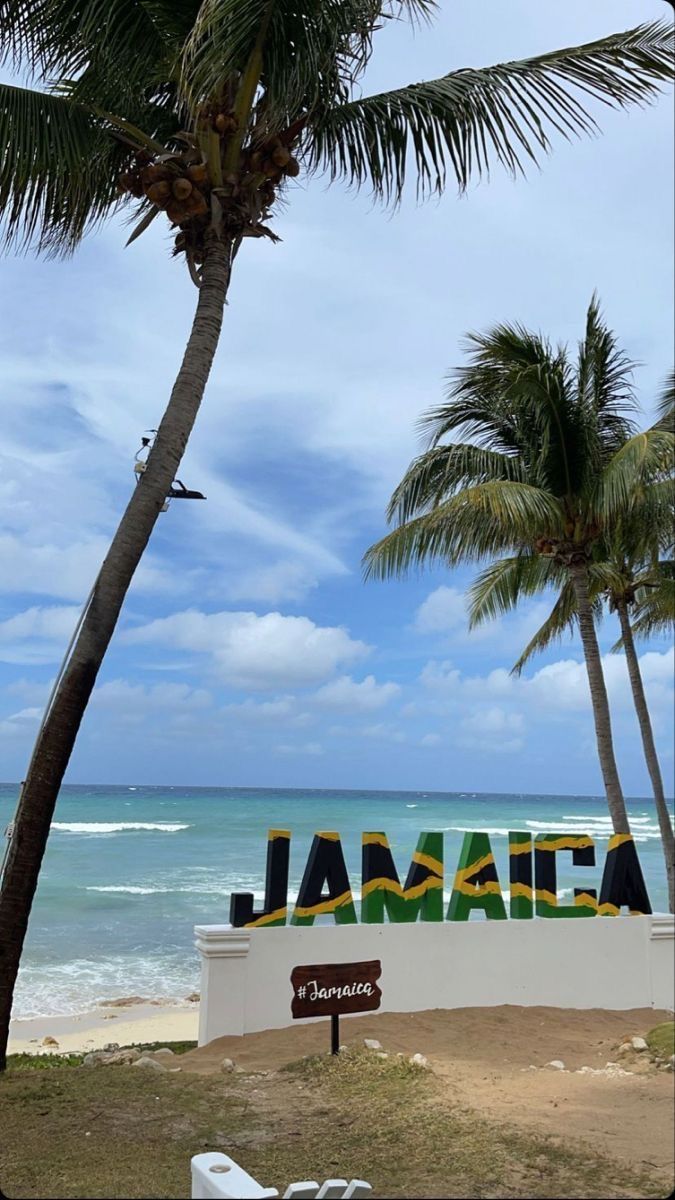 there is a sign that says jamaica on the side of the beach with palm trees