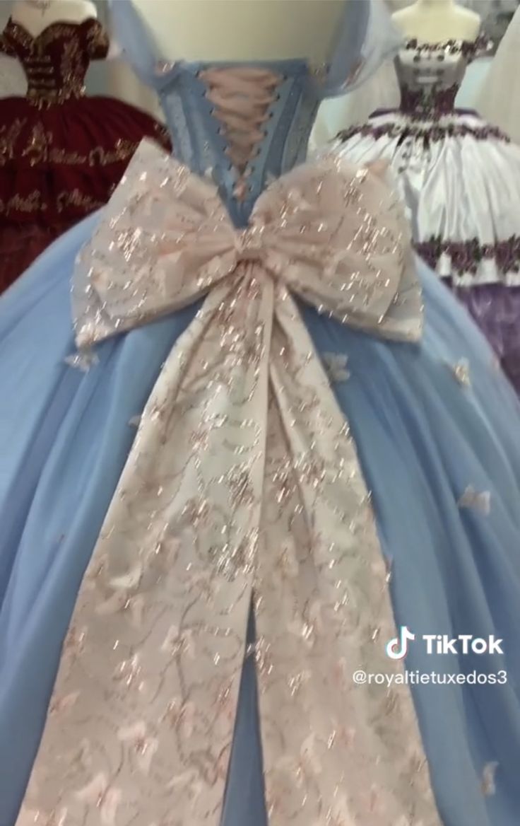 the dress is blue and has a large bow on it's back, while other dresses are in the background