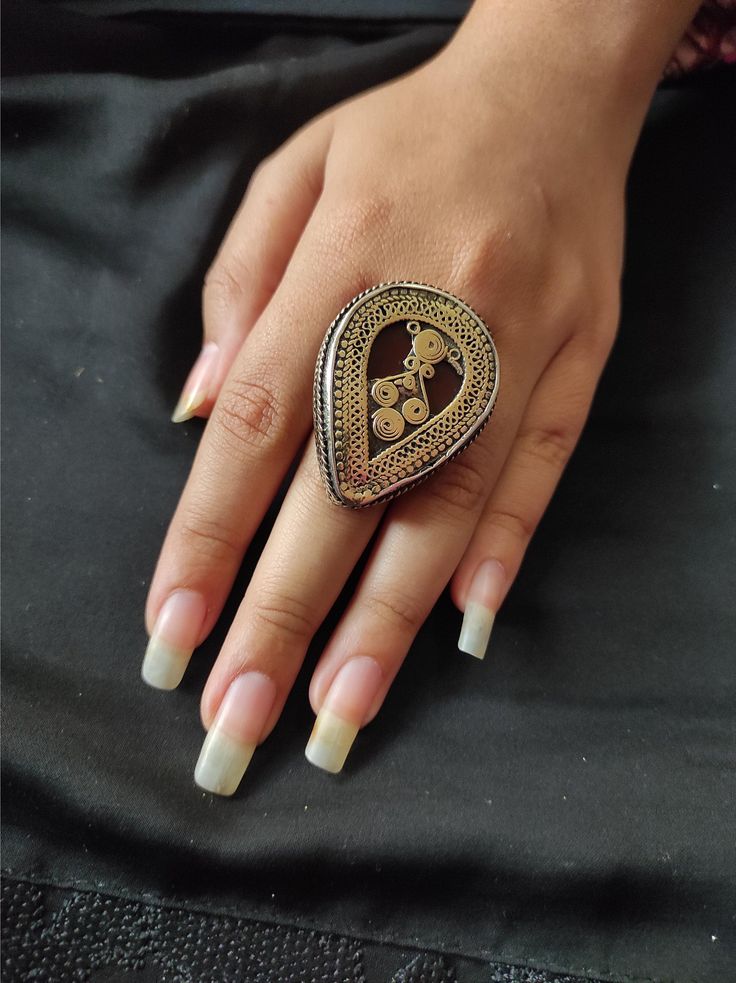 * This Afghani ring is truly embellished traditional ornament, inspired by the Kuchi style jewellery style. The delicate and fine motifs engraved all over the ring in the silverish tone are going in contrast with antique bright colour stones, embedded within the centre of the ring. Make it part of your traditional jewellery collection and make yourself look beyond just good in the coming event. Adjustable Ring Note: The product is handmade, so slight change might occur in the actual product.