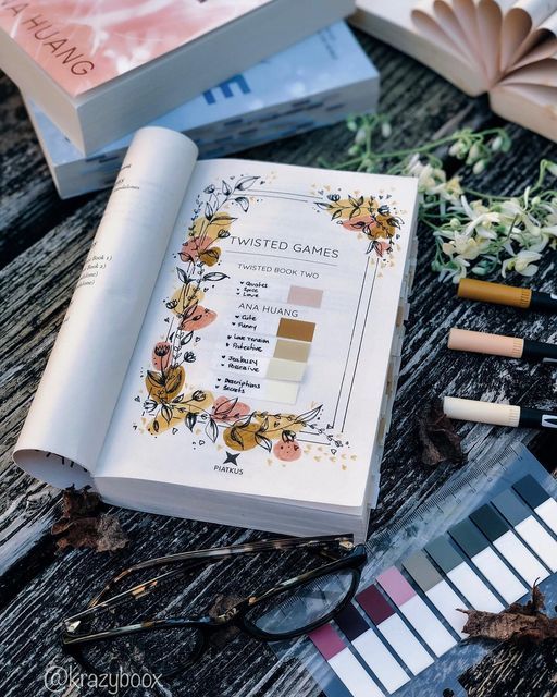 an open book sitting on top of a wooden table next to some flowers and other items