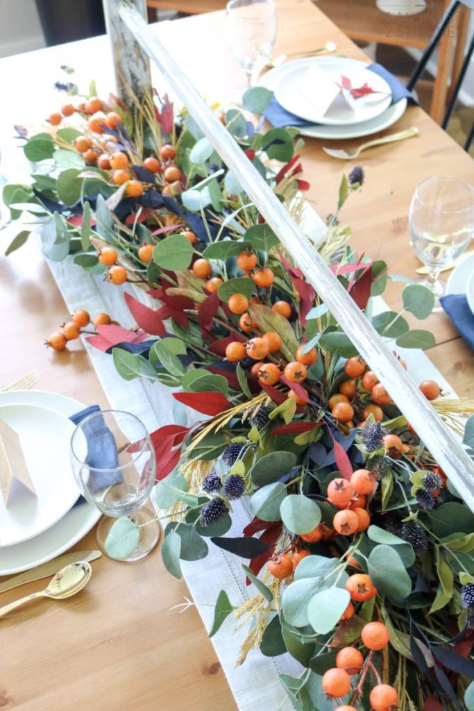 the table is set with plates, silverware and oranges on it's edges